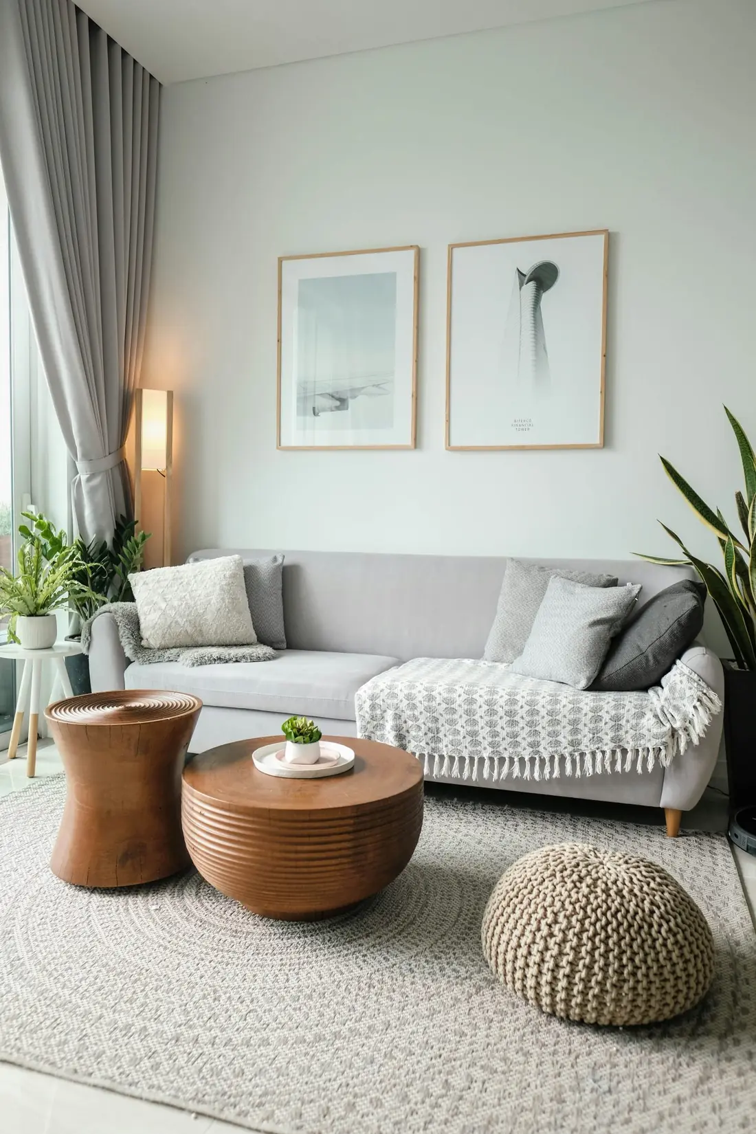 A bright, tidy living room with a grey sofa and wooden side tables